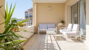 A balcony with a sofa, chairs, and potted plants.