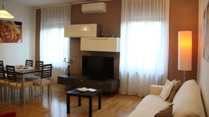Een moderne woonkamer met een flatscreen televisie, eettafel en een bank.