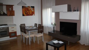 Een moderne keuken met een eethoek, een flatscreen-tv en een vaas met bloemen op een tafel.
