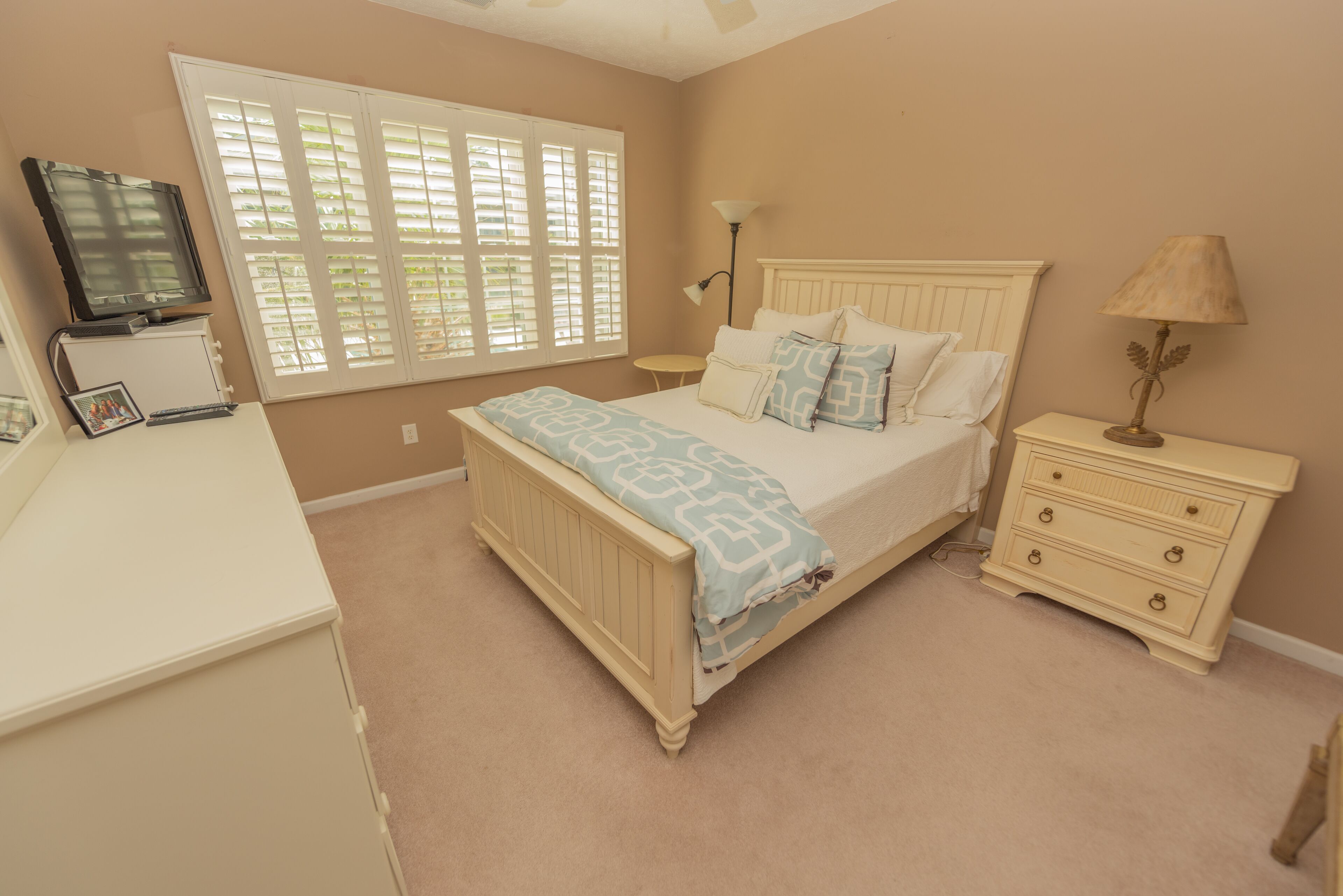 A bedroom with a bed, bedside table, lamp, and a television on a stand.