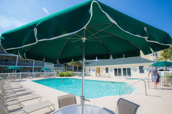 A poolside area with lounge chairs, a pool, and a building in the background.