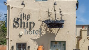 Un edificio con un letrero que dice "the Ship hotel" y un adorno de timón.