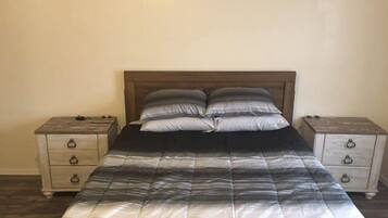 Un dormitorio con una cama, dos mesitas de noche y un cabecero de madera.