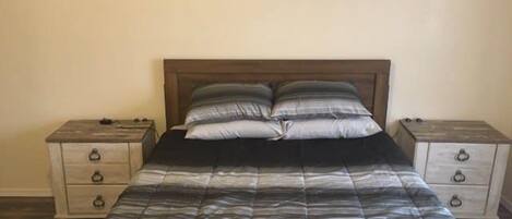 Une chambre à coucher avec un lit, deux tables de chevet et une tête de lit en bois.