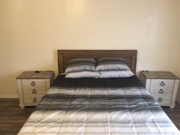 A bedroom with a bed, two nightstands, and a wooden headboard.