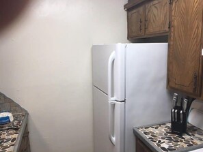A kitchen with a white refrigerator, wooden cabinets, and a tiled backsplash.