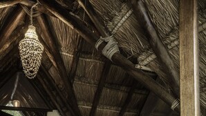 A bedroom with a wooden ceiling, a bed with white and dark bedding, and a hanging light fixture. - Boutique Resort in Mayan Jungle, Solferino, Quintana Roo (Solferino)