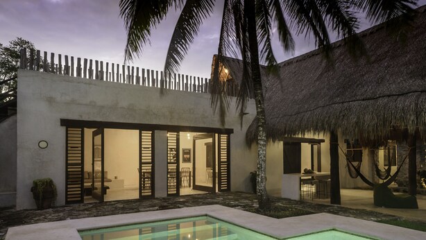 A modern villa with a pool, open doors leading to a dining area, and a thatched-roof structure. - Boutique Resort in Mayan Jungle, Solferino, Quintana Roo (Solferino)