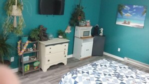 A teal-themed bedroom with a bed, a TV, a microwave, and various decorative items. - Monthly deals ,  #4  at Beach Mirage Suites  (Brook Park)