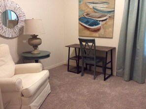 Cozy retreat with a single chair, small table, and a round mirror.