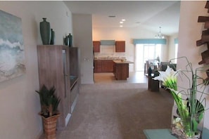 Experience the modern design of this stylish space, featuring a kitchen area with a central island and a hallway leading to a cozy atmosphere.