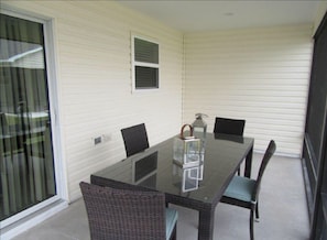 Enjoy meals at the glass-top dining table surrounded by four chairs, with a sliding glass door leading to an outdoor area.