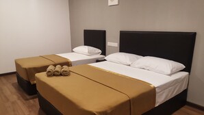 A hotel room with two beds, each with a black headboard and white bedding. There are two bedside tables, one on each bed, and a small nightstand on the right side of the room. - Belmorris Greentown Hotel (Ipoh)