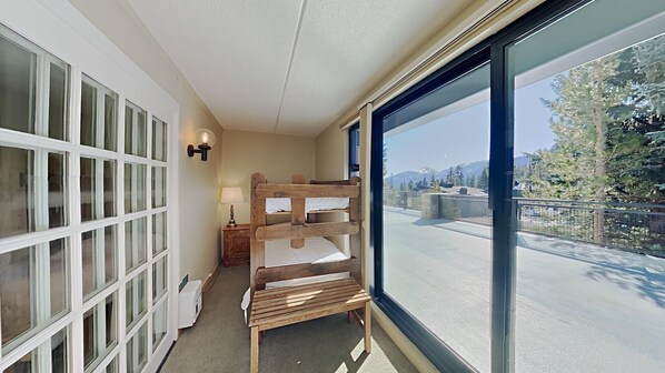 Enjoy a peaceful retreat with a bridge view from this cozy corner room, featuring a comfortable bunk bed and a bedside table with a lamp.