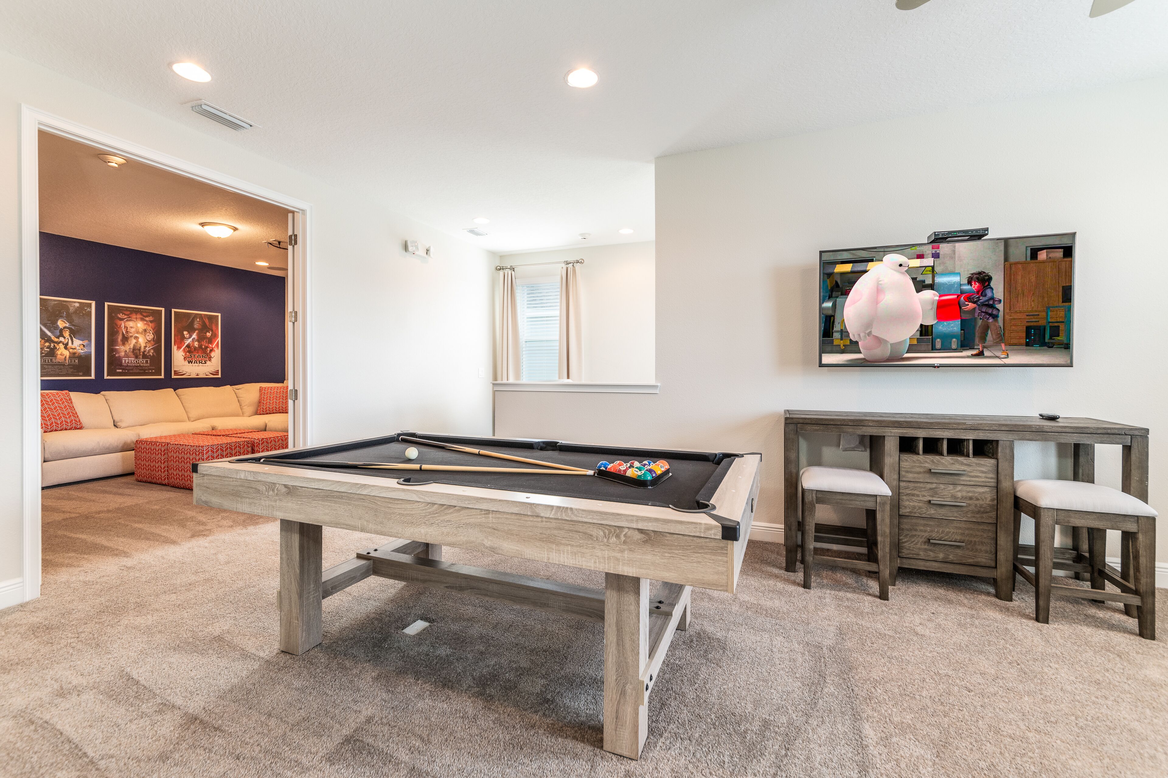 A pool table in a room with a sofa and a desk.