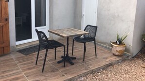 An outdoor patio with a wooden table and two chairs, a potted plant, and a door. - INDEPENDENT ROOM IN RESIDENCE PORTO VECCHIO (Porto-Vecchio)