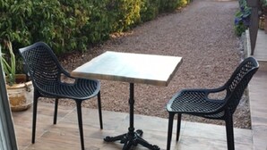An outdoor patio with a table and two chairs, surrounded by a garden and a wooden fence. - INDEPENDENT ROOM IN RESIDENCE PORTO VECCHIO (Porto-Vecchio)