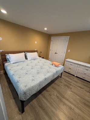 Un dormitorio con cama, mesita de noche, cómoda y una puerta.
