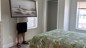 Een slaapkamer met een bed, een schilderij aan de muur en een hond in de ruimte.
