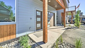 A modern house with a covered porch, wooden beams, and a flag. - Bozeman Stand-Alone Home w/ River Access! (Bozeman)
