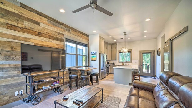 A modern living room with a leather sofa, a wooden coffee table, and a TV on a wooden stand. - Bozeman Stand-Alone Home w/ River Access! (Bozeman)
