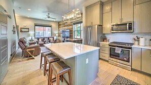 A modern kitchen with a large island, stainless steel appliances, and a dining area with leather chairs. - Bozeman Stand-Alone Home w/ River Access! (Bozeman)