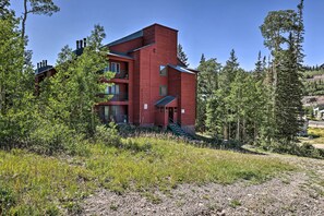 Un bâtiment rouge à étages, entouré d’arbres et d’une zone herbeuse.