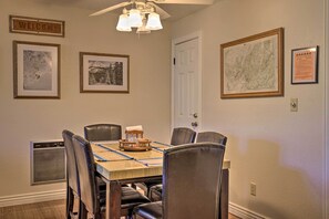 Une salle à manger avec une table en bois, six chaises et des tableaux encadrés accrochés aux murs.