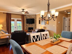 A dining area with a wooden table, white chairs, and a chandelier.