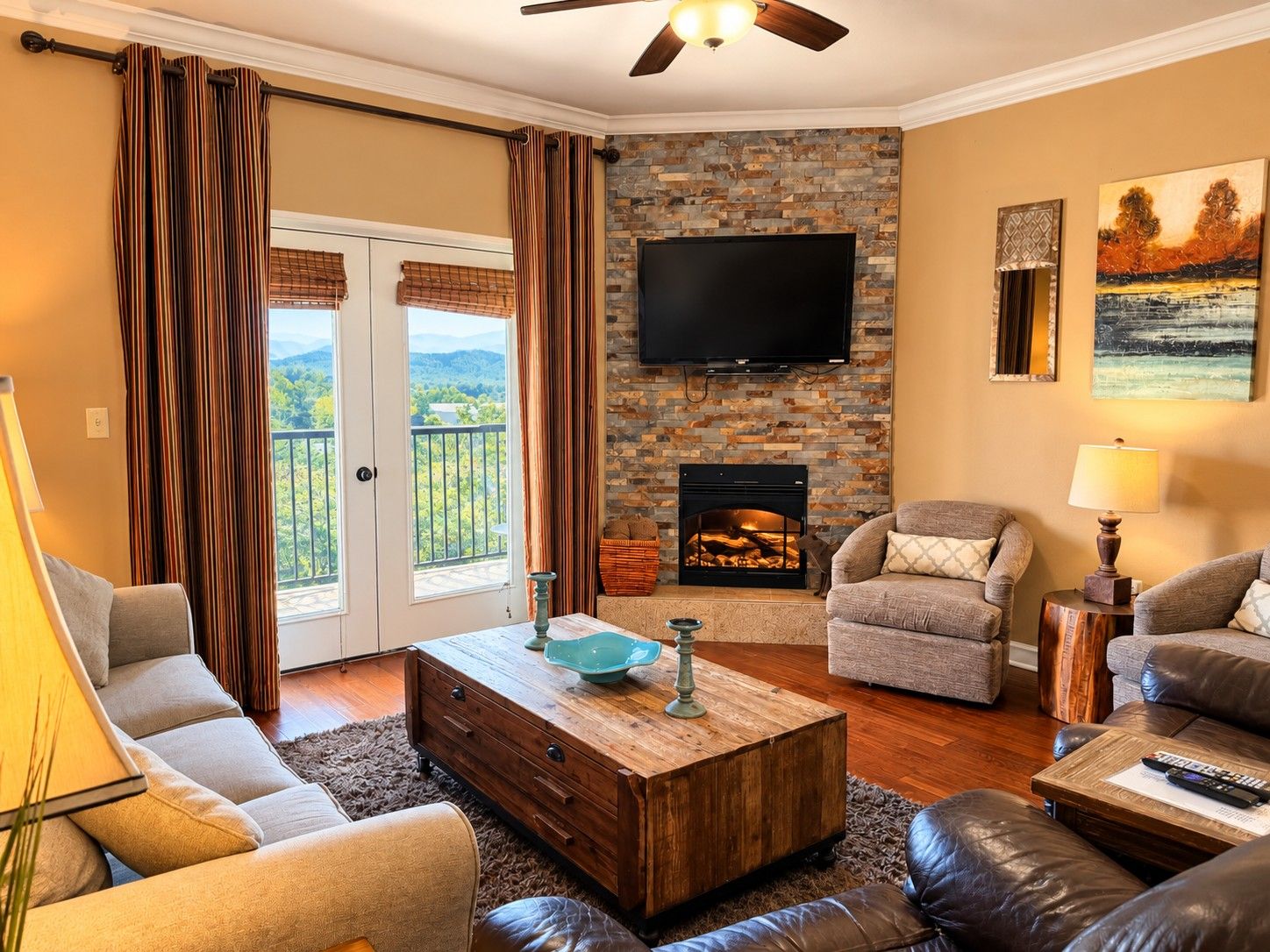 A living room with a fireplace, a television, and a balcony with curtains.