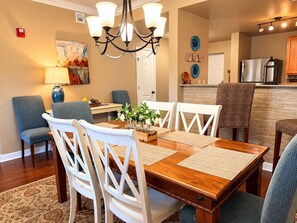 A dining area with a wooden table, white chairs, and a chandelier.