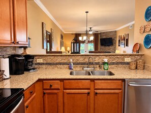 A kitchen with wooden cabinets, a granite countertop, a stainless steel sink, and a built-in oven.