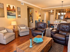 A living room with a sofa, two armchairs, a coffee table, and artwork on the walls.