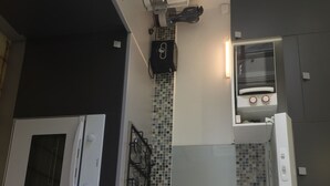 A kitchen with a microwave, stove, and oven. There is a tiled backsplash and a small shelf with jars. - Villa Quietude (Saint François)