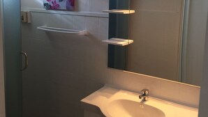 A bathroom with a white sink, a mirror, and a shelf with a floral painting. - Villa Quietude (Saint François)