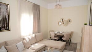 Un saló modern amb un sofà seccional beix, una taula de centre rodona i una zona de dinar amb taula i cadires.