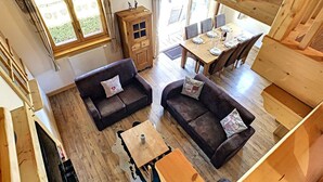 Een ruime woonkamer met twee donkere banken, een houten salontafel en een eettafel gedekt voor vier personen.