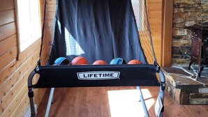 Un panier de basket avec deux panneaux arrière portant les inscriptions « DOMICILE » et « EXTÉRIEUR » et une pancarte indiquant « À VIE ».