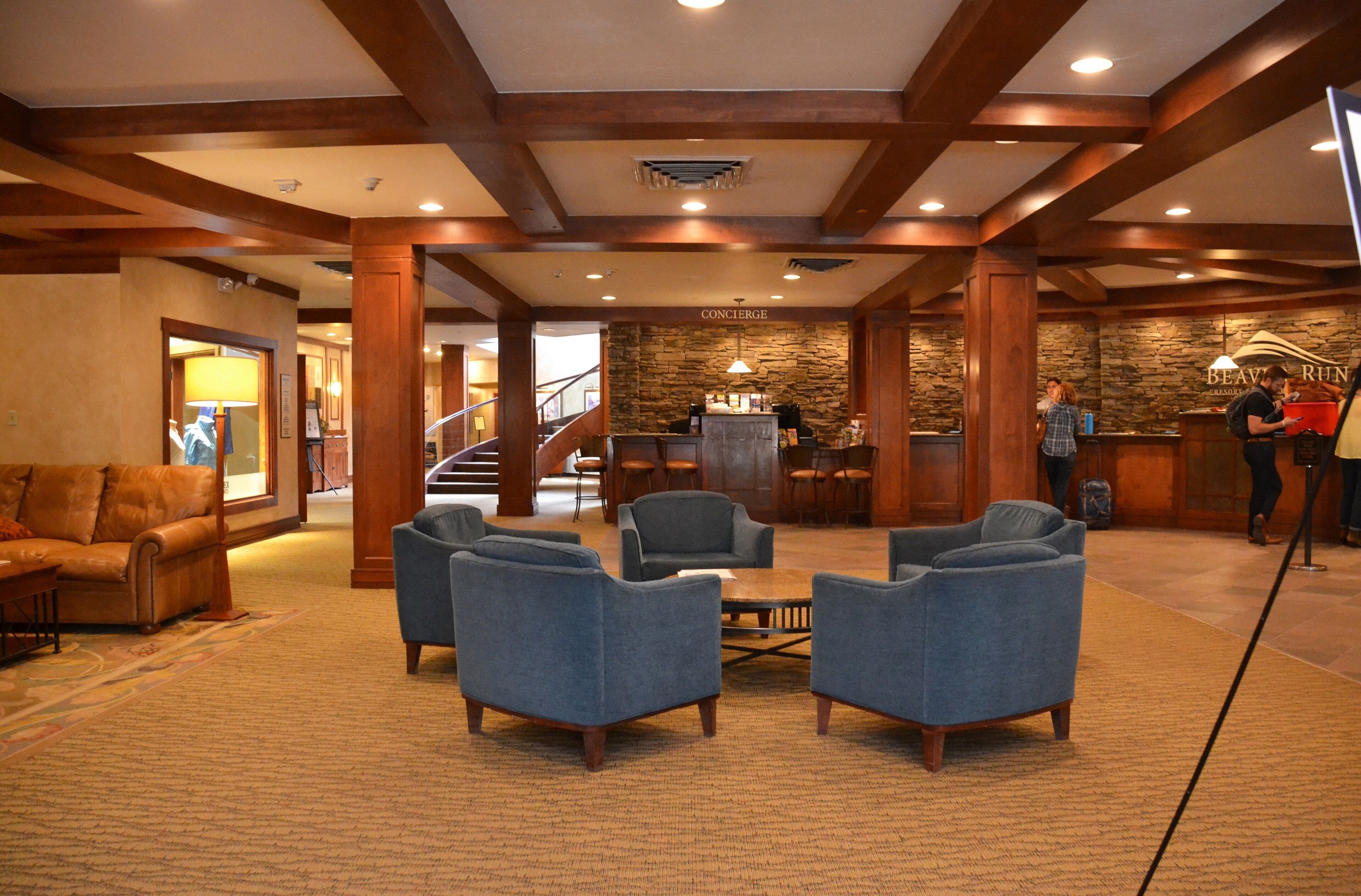 A lobby with a stone wall, wooden beams, a reception desk, and a staircase.