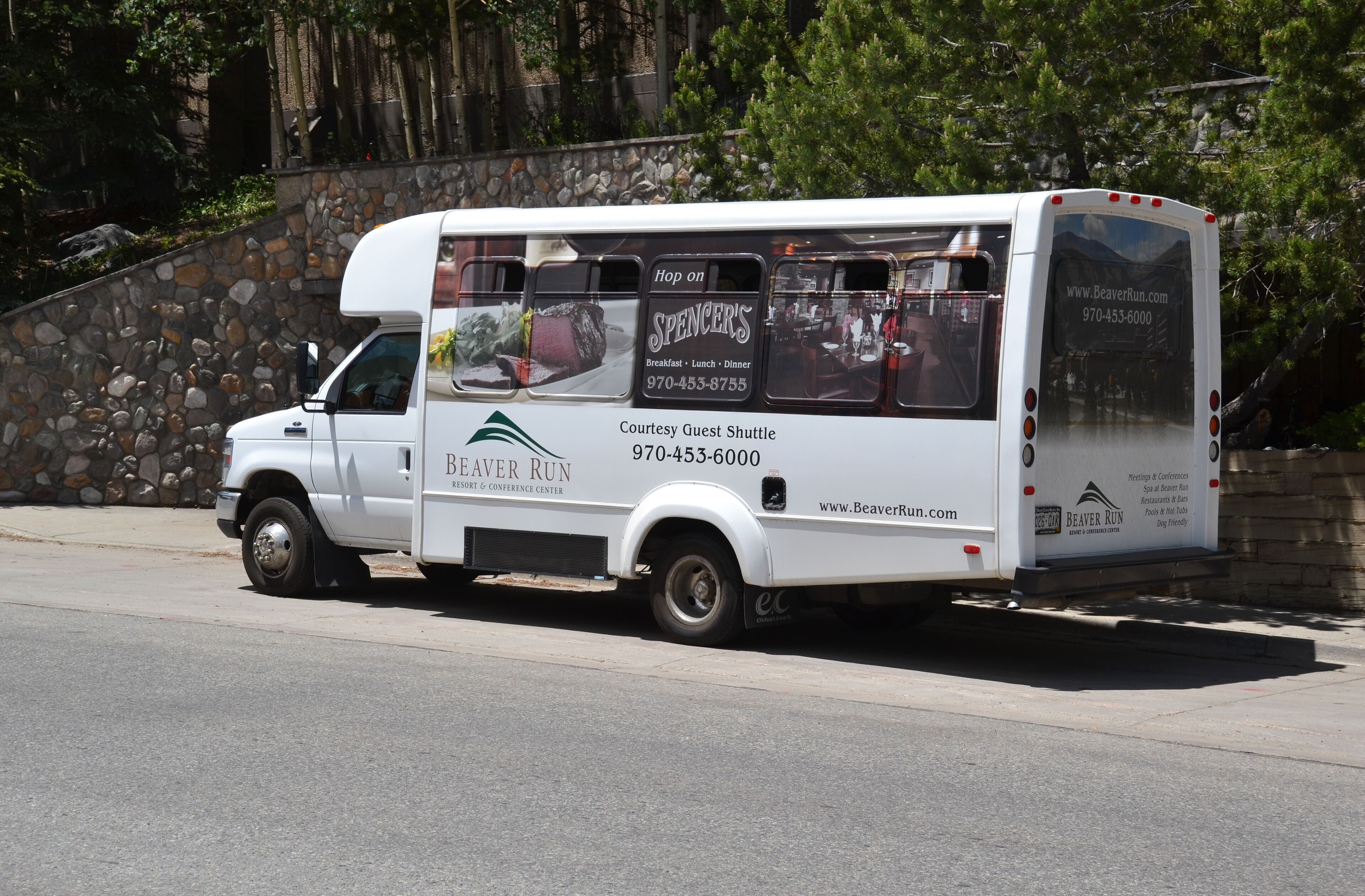 A white shuttle bus with "Beaver Run" branding and contact information for guest shuttle services.