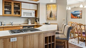 Une cuisine moderne avec des meubles en bois, un four à micro-ondes encastré et une cuisinière à gaz. On y trouve également un coin repas avec des chaises et une table en bois.