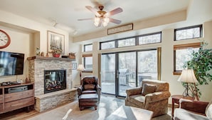 A spacious living room with a fireplace, comfortable seating, a television, and large windows offering views of the outdoors. - Stunning Breckenridge Townhome with Private Hot Tub, Garage! (Breckenridge)