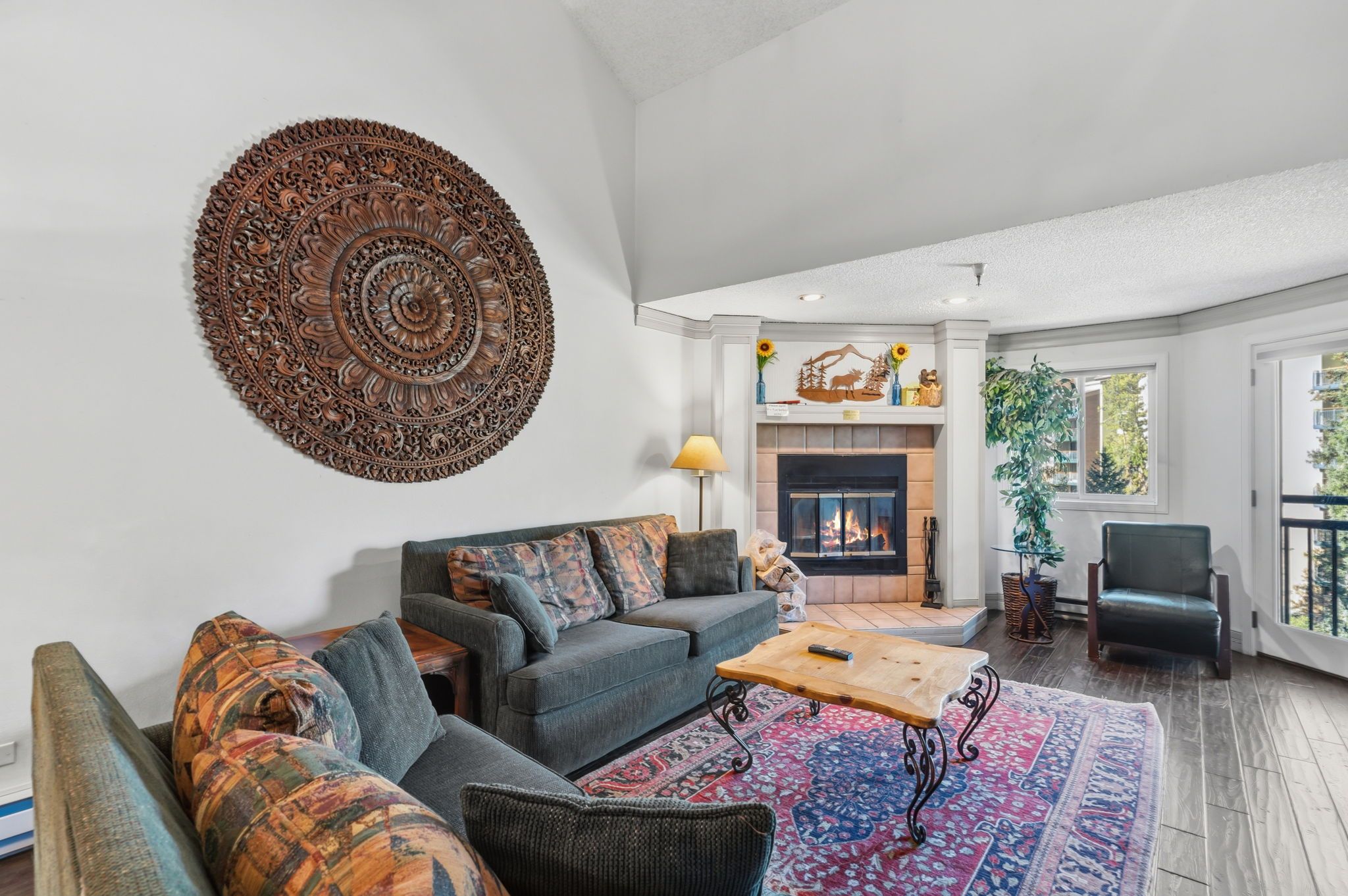 Un salon spacieux doté d’une cheminée, d’une grande décoration murale et offrant une vue sur l’extérieur.