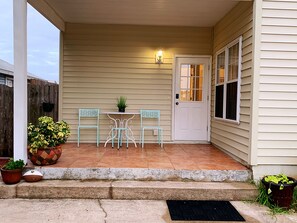 Step outside to a charming porch with a door, two chairs, and a small table.