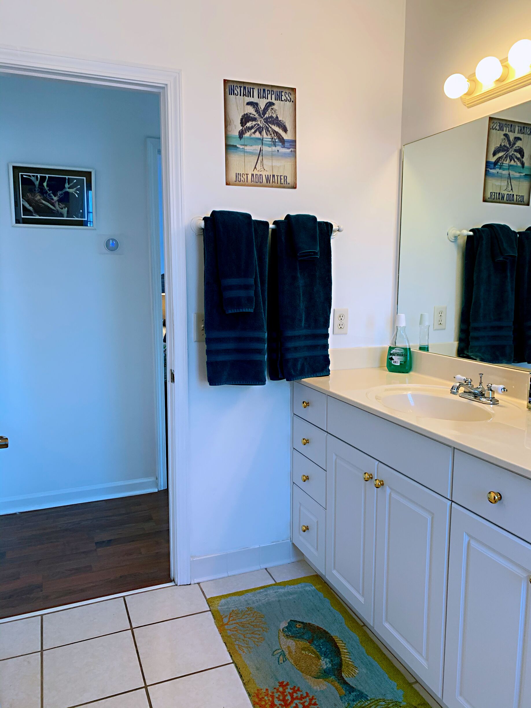 A bathroom with a white sink, a mirror, and two towels hanging on a rack.