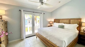 A bedroom with a bed, a ceiling fan, a nightstand, a dresser, and a window with curtains.