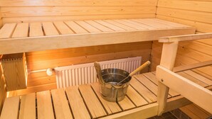 A sauna with wooden benches and a metal bucket.