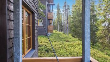 A wooden cabin with a balcony overlooking a forested area.