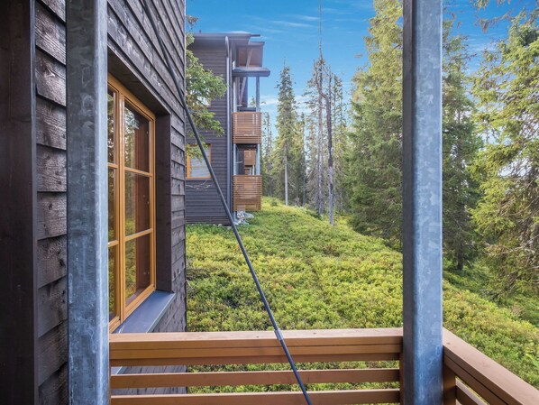 A wooden cabin with a balcony overlooking a forested area.