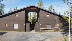 A modern building with a large entrance, wooden exterior, and a gravel driveway.